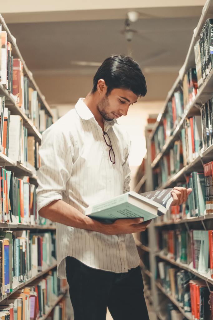 Image of a male student in library stacks.