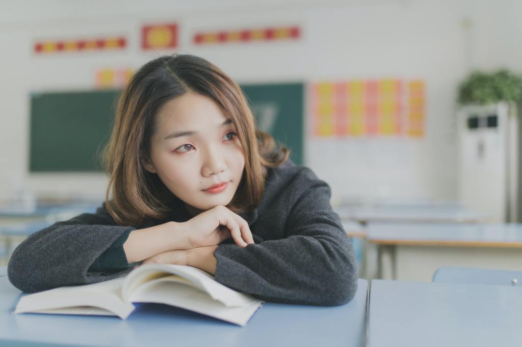 Image of a young female student leaning on an open book.